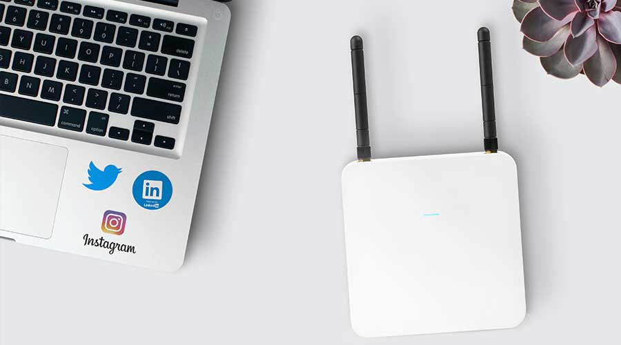 A wifi extender next to a laptop. Buy one with one of the best routers under 100.